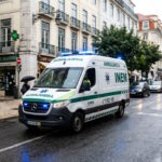 Ambulance driving through a European city street, highlighting the importance of healthcare infrastructure for residents and expatriates