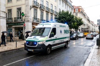 Ambulance driving through a European city street, highlighting the importance of healthcare infrastructure for residents and expatriates
