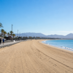 Quiet beach promenade during the off-season with only a few joggers and an empty coastline under a clear blue sky