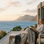 Woman relaxing on a private terrace overlooking the sea, representing modern luxury travel focused on time, space and privacy