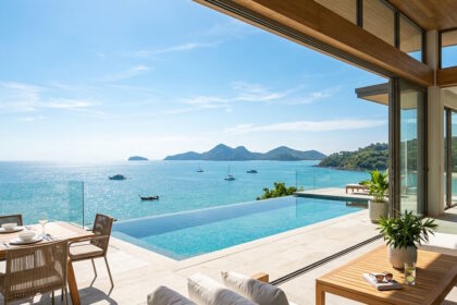 Modern luxury villa terrace with an unobstructed panoramic ocean view under a clear blue sunny sky.