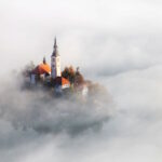 Lake Bled and its island church emerging through the morning mist in Slovenia