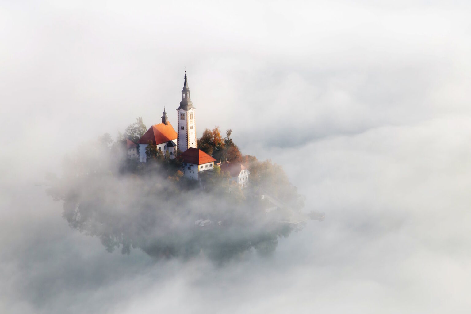 Lake Bled and its island church emerging through the morning mist in Slovenia